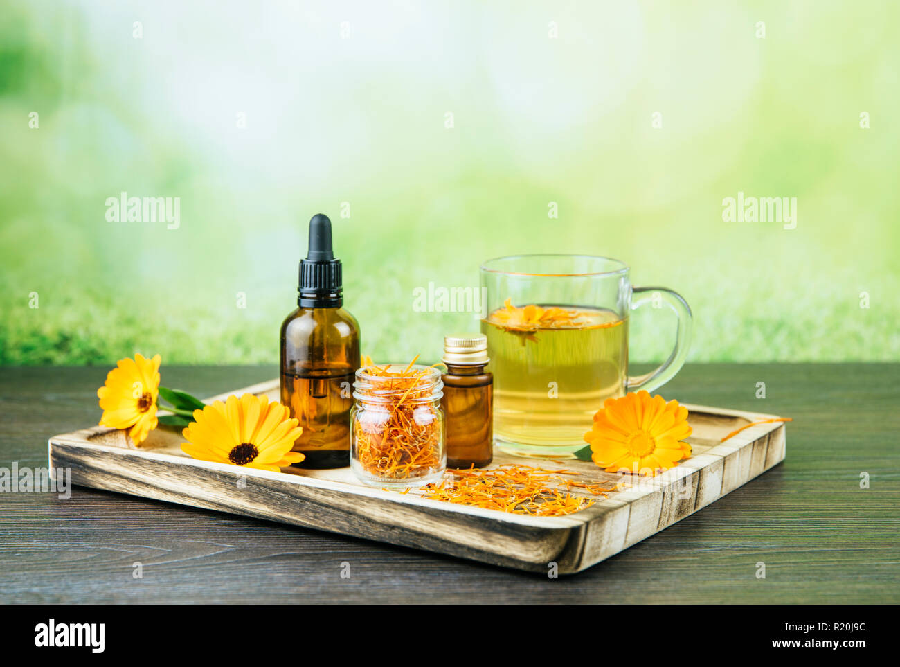 Calendula officinalis, le souci officinal, ruddles, marigold commun ou Scotch marigold différents produits de santé sur le plateau en bois, huile essentielle, teinture Banque D'Images