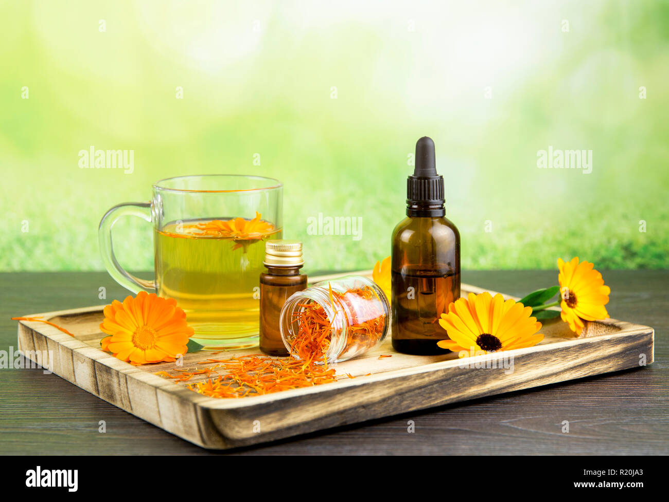 Calendula officinalis, le souci officinal, ruddles, marigold commun ou Scotch marigold différents produits de santé sur le plateau en bois, huile essentielle, teinture Banque D'Images