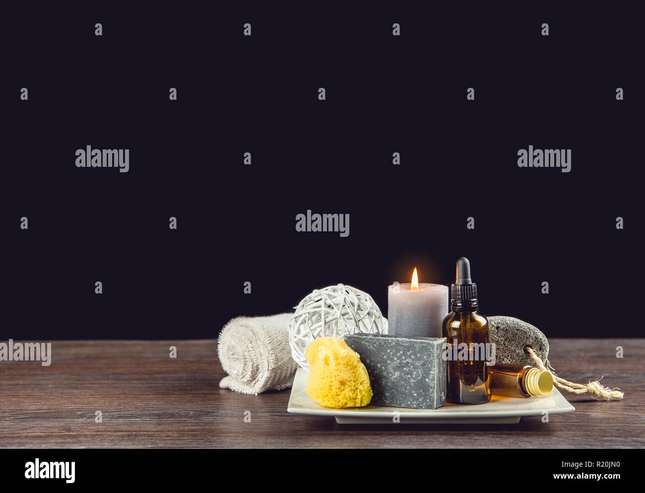 Homme spa relaxation concept. Spa de jour différents produits sur le plateau en céramique blanche sur table en bois foncé, fond noir. Banque D'Images