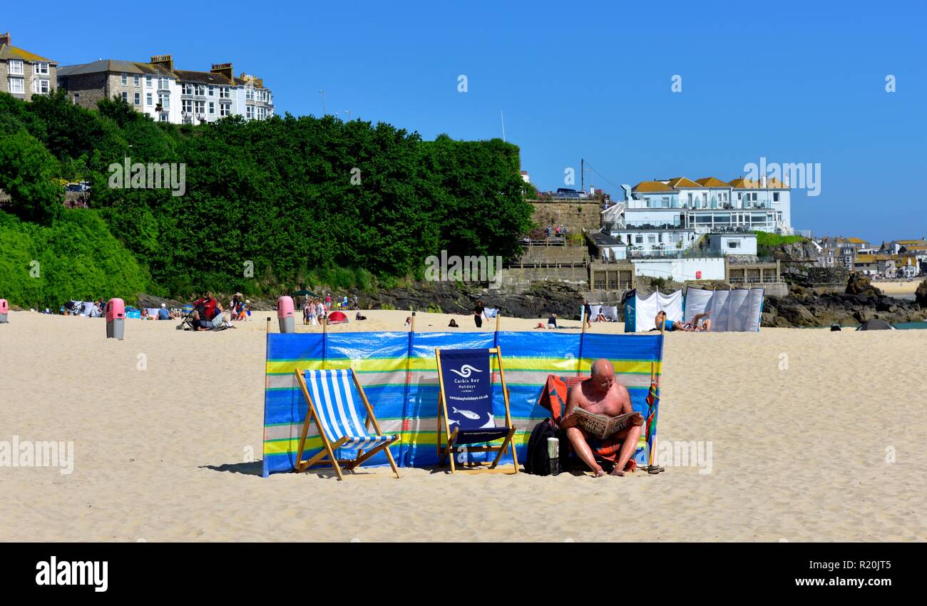 Retraite Senior homme lisant un journal sur la plage de Porthminster, Cornwall, Angleterre, Royaume-Uni Banque D'Images