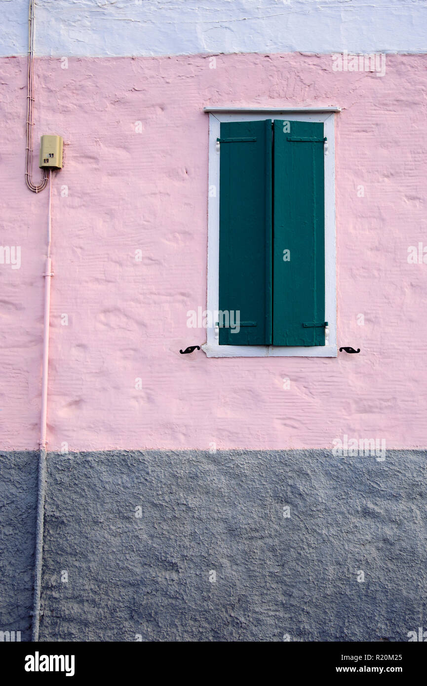 Volets vert foncé sur un mur crépi extérieur tricolore. L'île grecque de Tinos. Banque D'Images