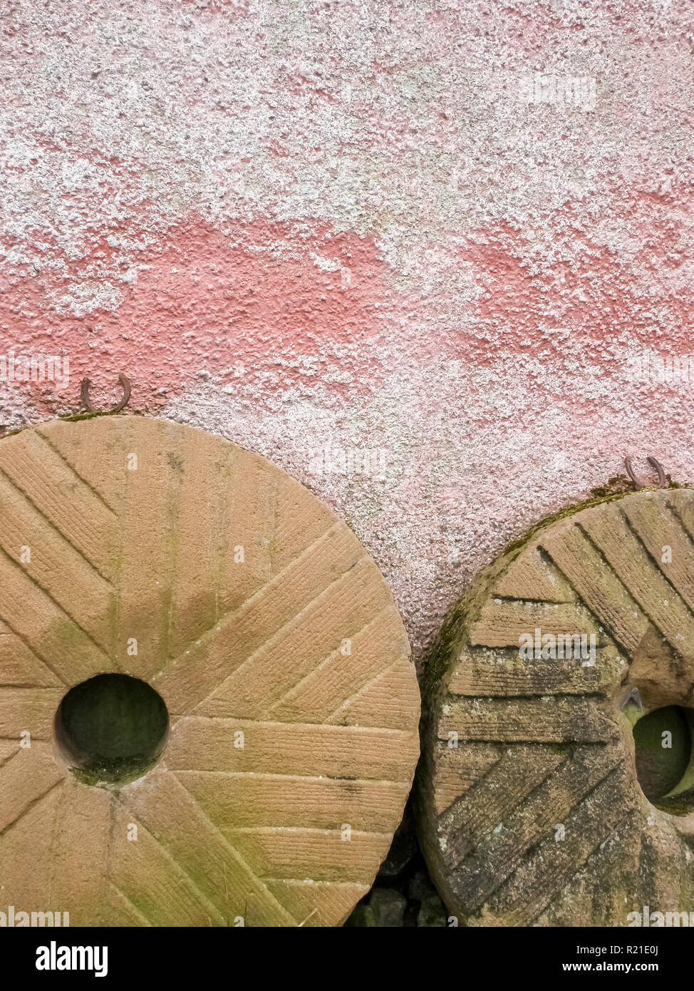 Deux vieilles meules appuyé contre le mur d'une grange ou expier mill house près de Greystoke, Cumbria, Royaume-Uni Banque D'Images