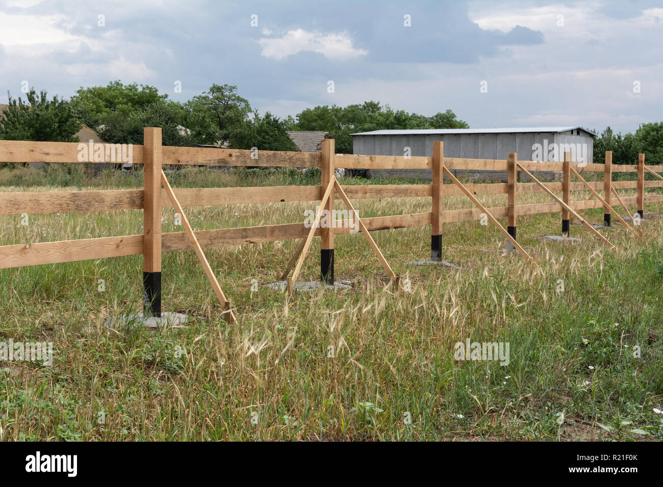 Clôture de style ranch. Clôture en bois en milieu rural sur l'herbe verte au niveau de l'exploitation des terres du ranch dans Shagany, Ukraina. Banque D'Images
