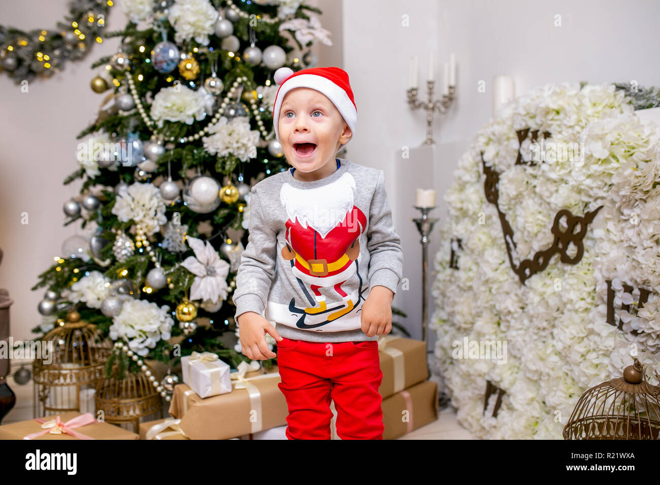 Heureux jeune famille, père, mère et fils, dans la soirée de Noël dans la maison. Un petit garçon dans Santa's hat se tiennent près de l'arbre avec des cadeaux, d'émerveillement et de rire Banque D'Images