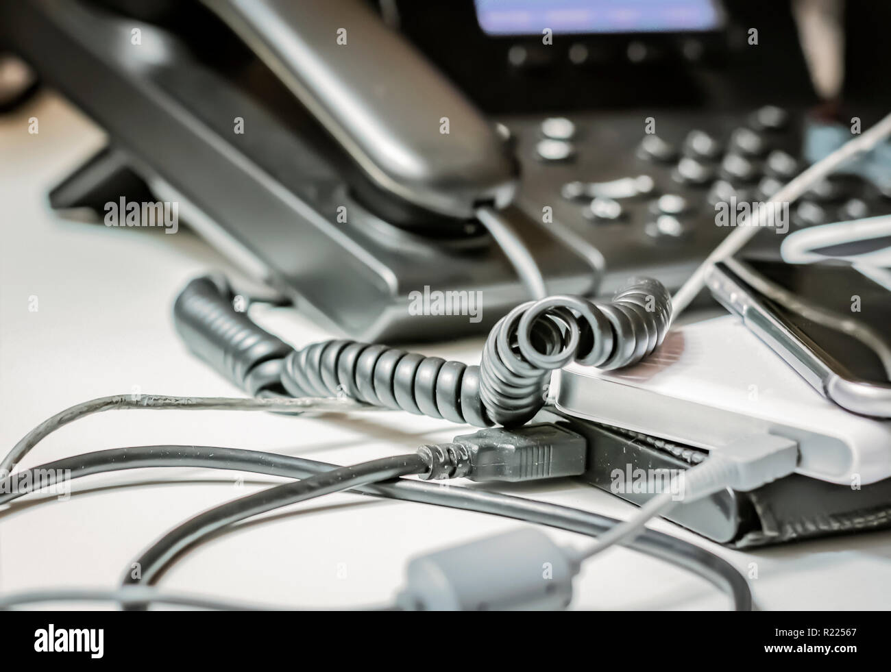 Twisted téléphone câble spirale et d'autres appareils branchés dans un office de tourisme Banque D'Images