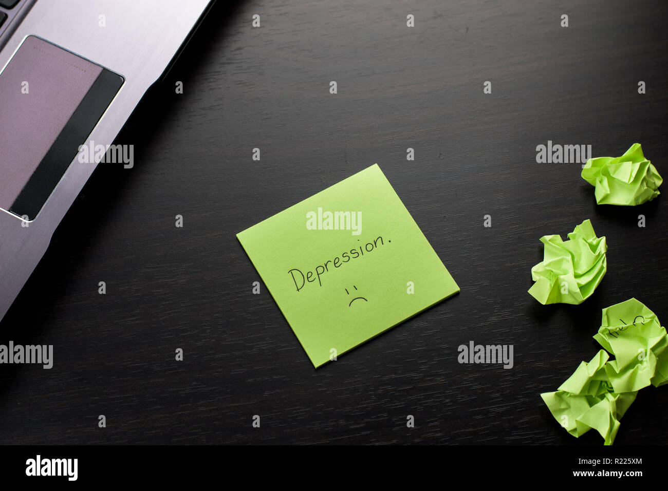 "Dépression" est écrit sur un post-it sur le tableau noir en bois. Vert froissé les notes sont dispersés et un ordinateur portable sur le côté. Banque D'Images