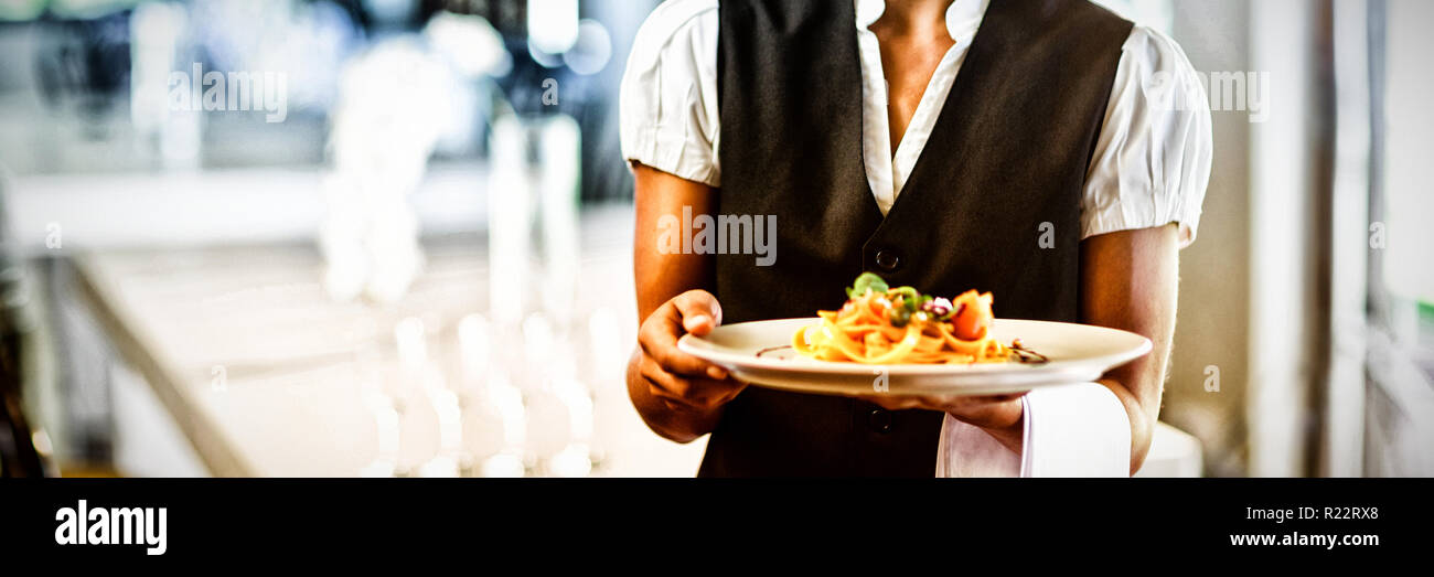 Waitress holding plate of repas au restaurant Banque D'Images