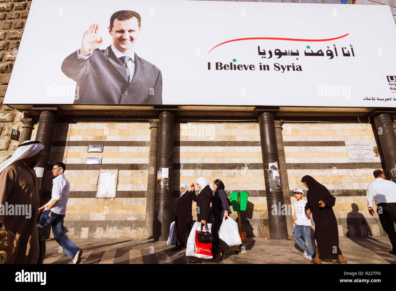 Damas, Syrie : les gens devant une du président de la Syrie Bachar al-Assad lecture je crois en Syrie. Banque D'Images