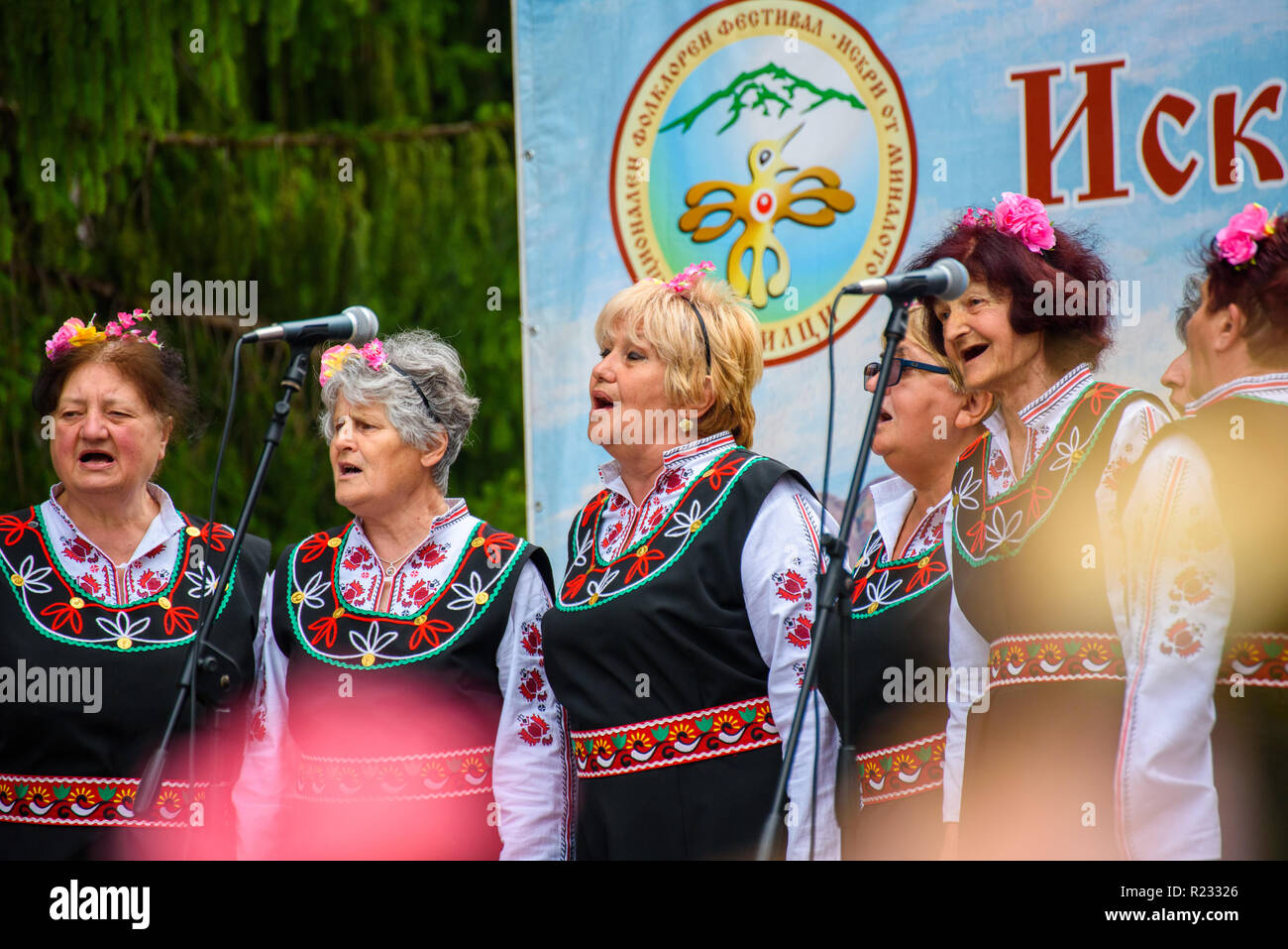 Groupe de femmes en costumes folkloriques bulgares traditionnels - chanter une chanson à un festival de musique dans la petite ville d'Apriltsi, Bulgarie. Banque D'Images