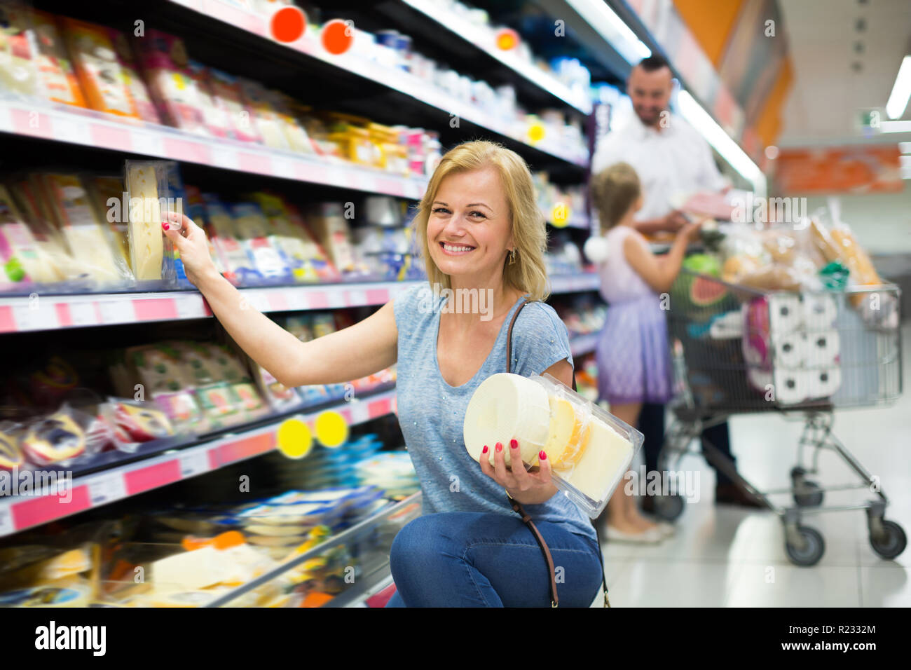 Cheerful female customer sélection fromage dans la section réfrigérée en hypermarché Banque D'Images