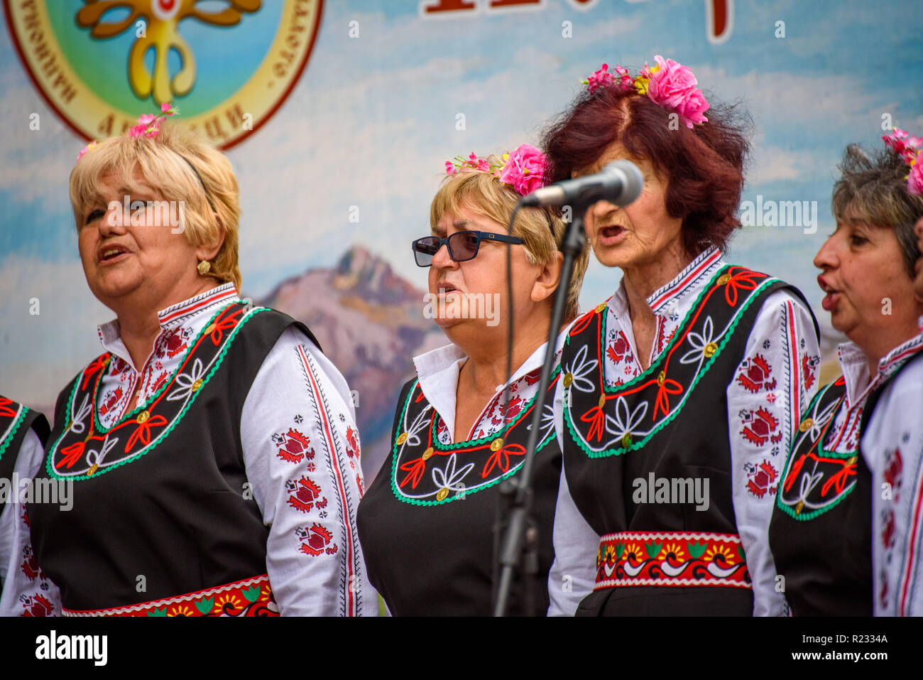 Groupe de femmes en costumes folkloriques bulgares traditionnels - chanter une chanson à un festival de musique dans la petite ville d'Apriltsi, Bulgarie. Banque D'Images