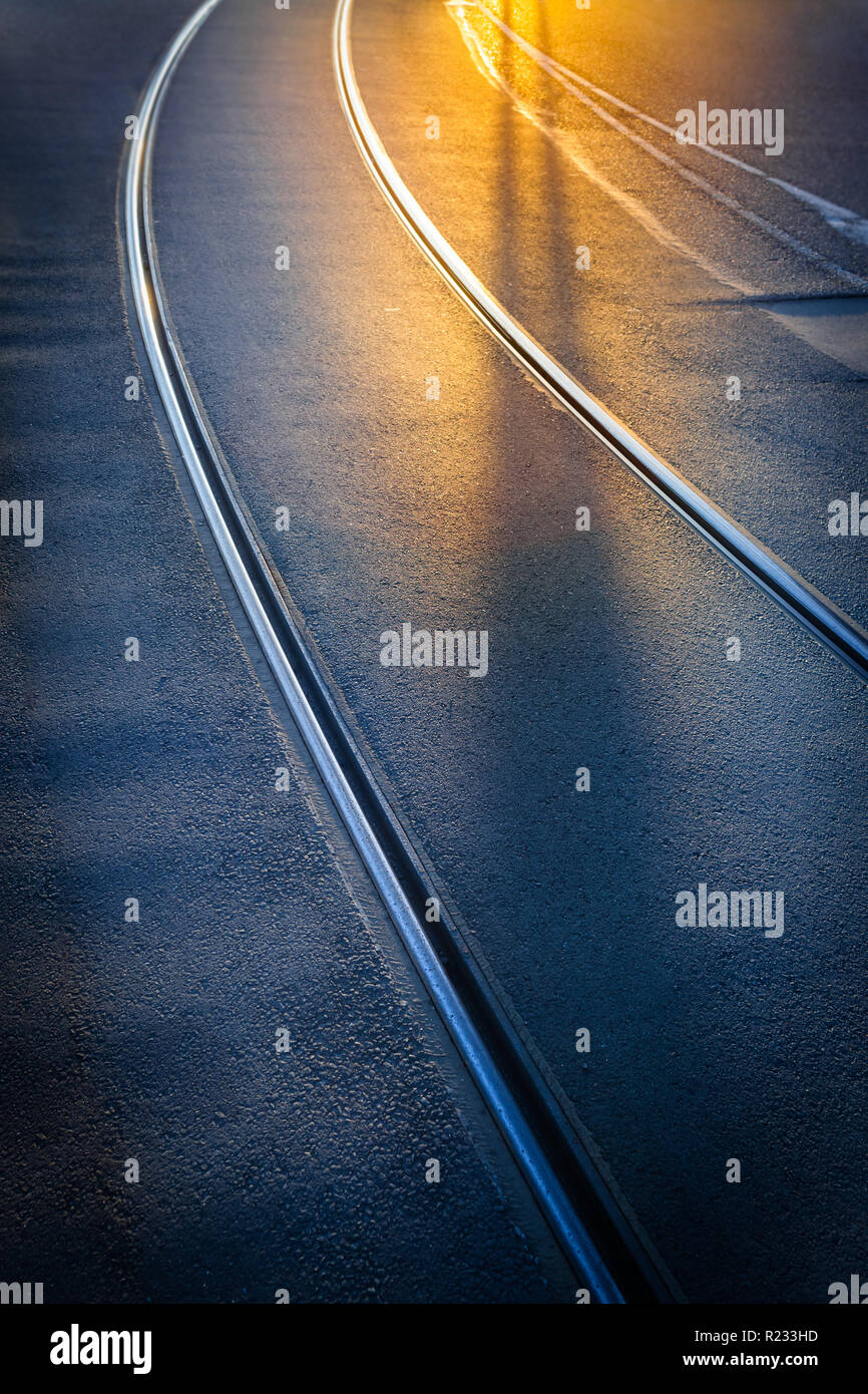 Contour flou du corps et de l'ombre de la jambe d'ossature de la personne qui marche à rails de tramway à la route d'asphalte contre le coucher du soleil la lumière (copie espace) Banque D'Images