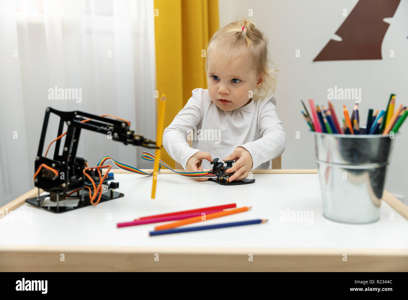 Petite fille jouant avec bras robot électronique à crayons de levage Banque D'Images