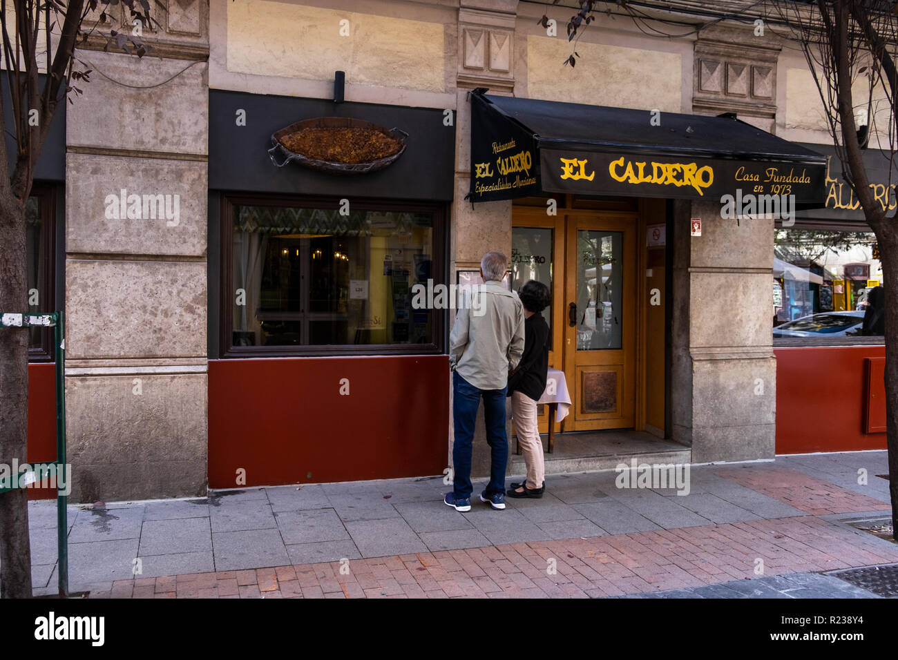 Le couple à l'extérieur du menu Restaurant El Caldero, Calle Huertas à Madrid, Espagne Banque D'Images