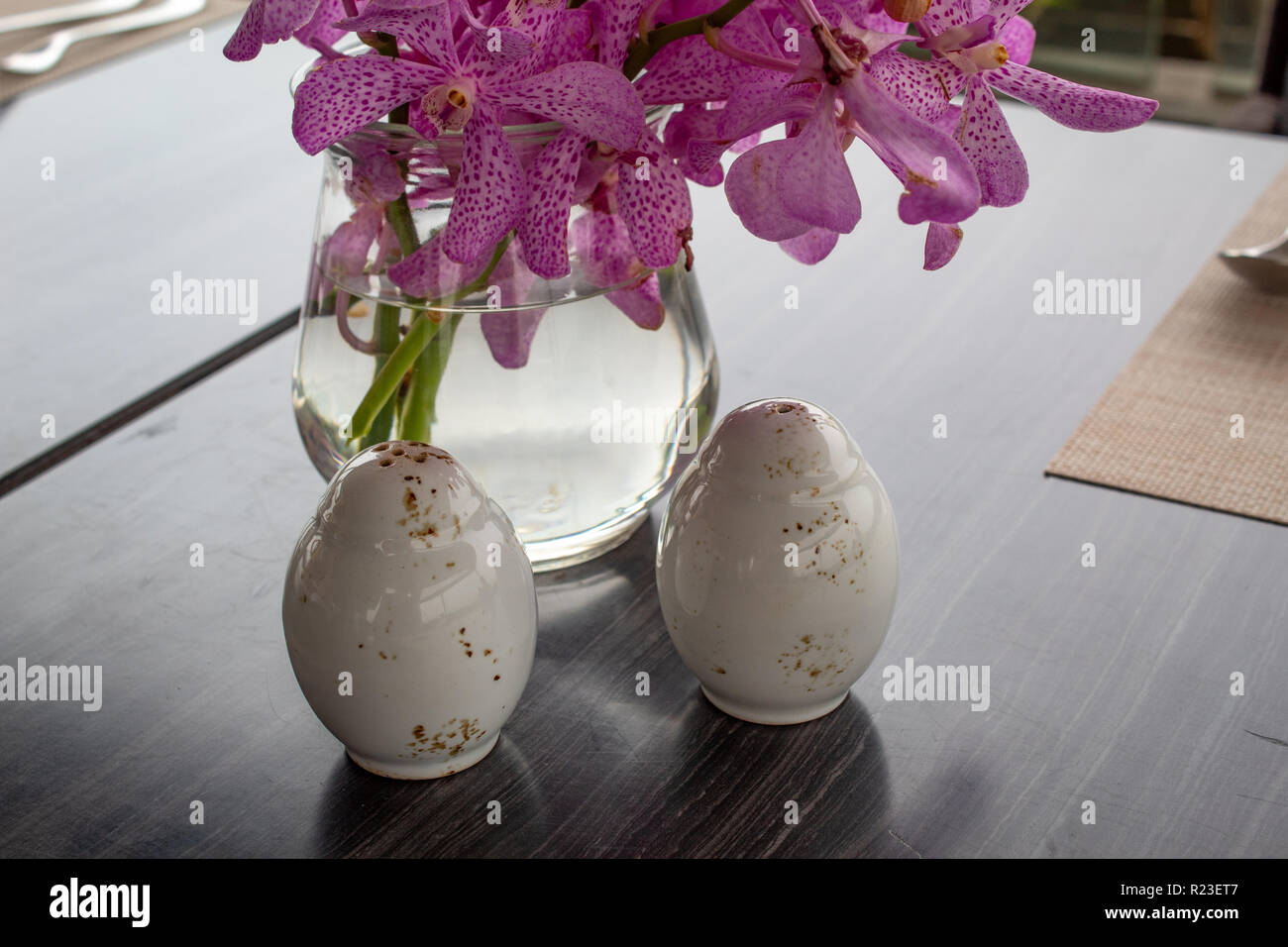 Sel et poivre Shaker en face de belles orchidées Banque D'Images