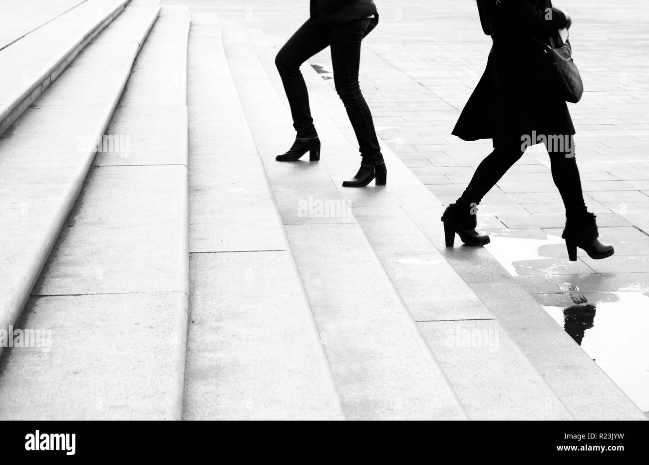 Deux jeunes femmes montent et descendent les escaliers ville énorme déménagement l'un devant l'autre, en noir et blanc Banque D'Images