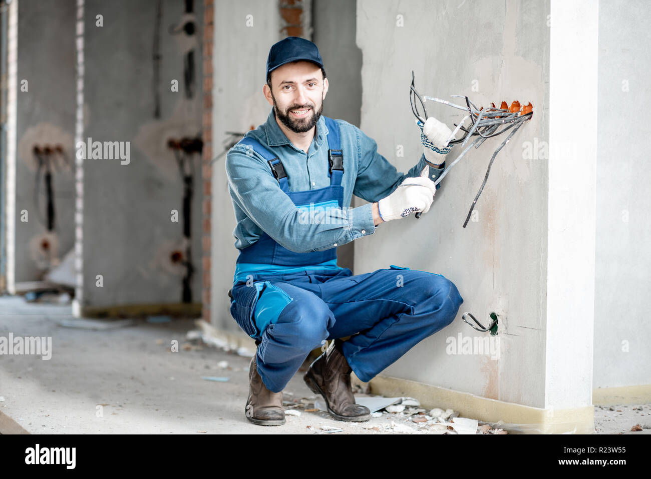 Portrait d'un électricien pour le câblage du support de prises électriques sur le site de construction d'un nouveau bâtiment à l'intérieur Banque D'Images