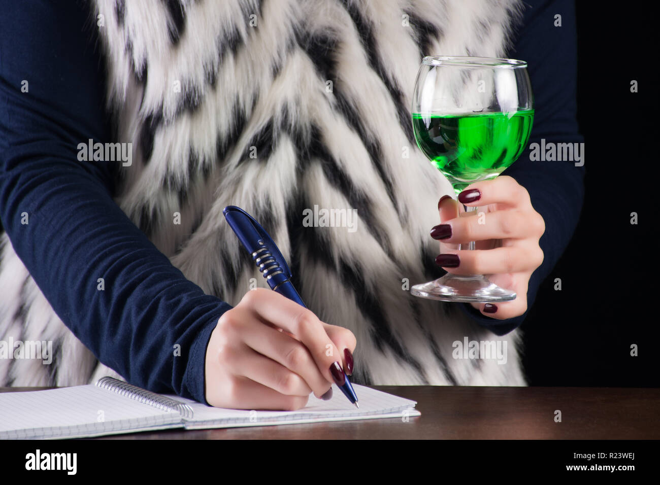 Businessman et détient l'alcool boire de l'absinthe à la main sur l'ancienne rétro bureau en bois. Fée Verte verre d'inspiration pour les écrivains. Close up Banque D'Images