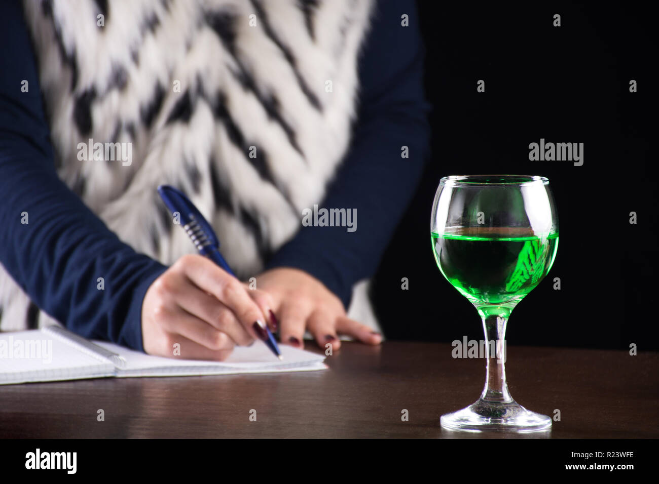 Vert Absinthe verre dans le verre et l'écriture femme histoire notebook en arrière-plan sur l'ancienne rétro bureau en bois. La fée verte d'inspiration et de muse pour writer Banque D'Images