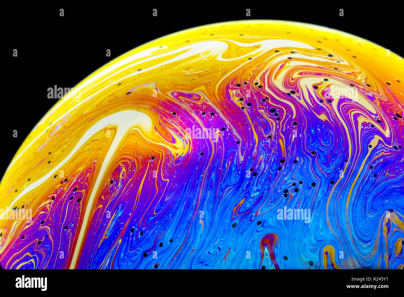 Couleurs arc-en-ciel de près dans une bulle de savon qui ressemblent à des planètes ou des mondes de l'espace ou isolé sur un fond noir Banque D'Images