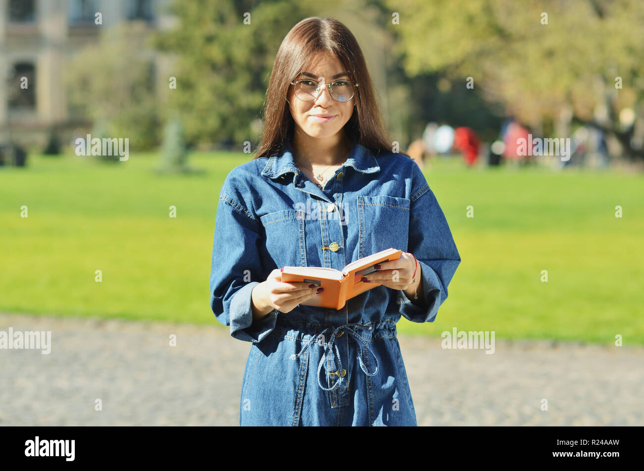 Smart college student avec des lunettes pour lire un livre sur le campus dans un parc historique Banque D'Images