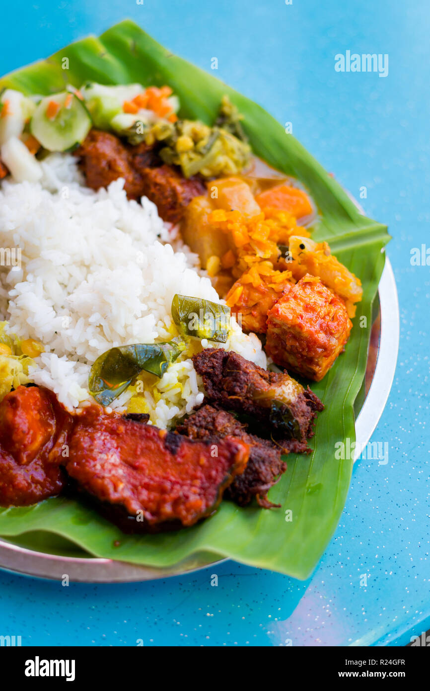 Sélection de produits frais préparés végétariens indiens les locaux de Malaisie servi sur des feuilles de banane en restaurant à Kuala Lumpur. Une cuisine traditionnelle en Asie Banque D'Images