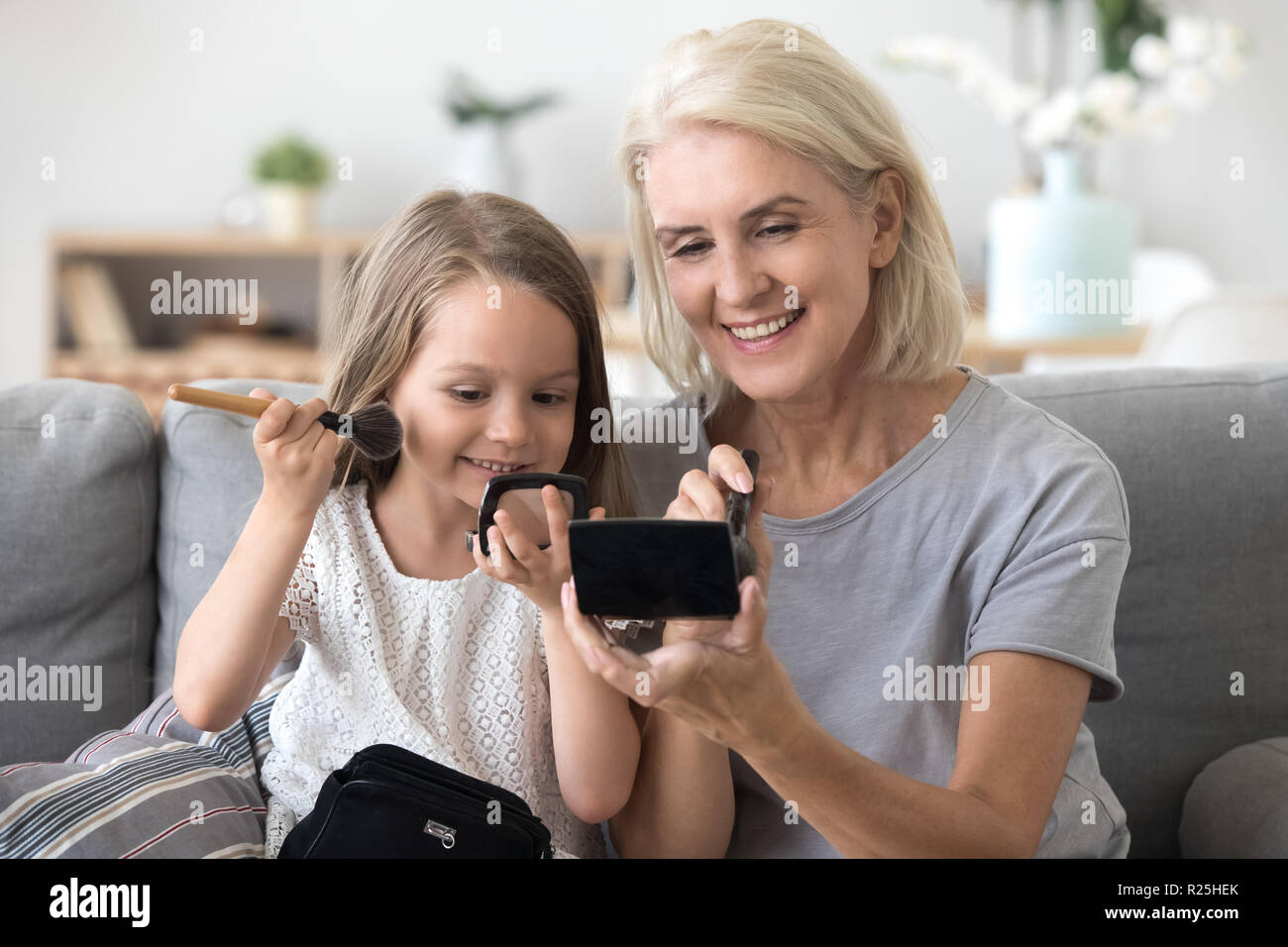 Petite-fille heureuse application blush s'amusant de faire un miroir avec Banque D'Images