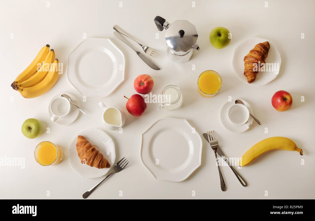 L'heure du petit-déjeuner. Des croissants et du jus d'orange, de la confiture et du miel. Café avec de la crème ou du lait. Fruits - bananes, pommes vertes et rouges. Le petit-déjeuner sur un t Banque D'Images