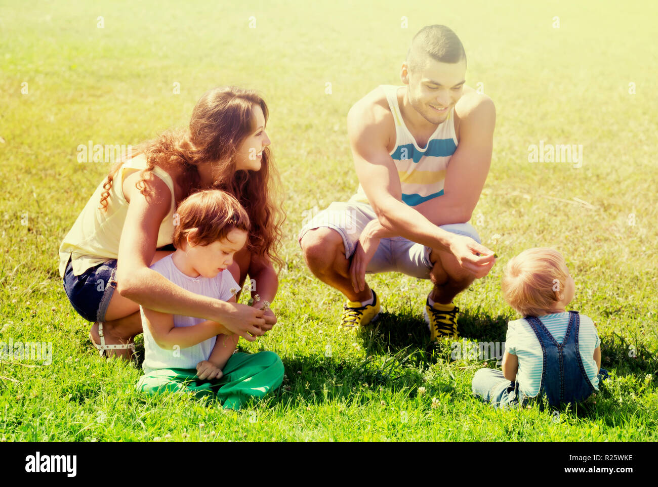 Famille heureuse de quatre se reposant dans sunny summer park Banque D'Images