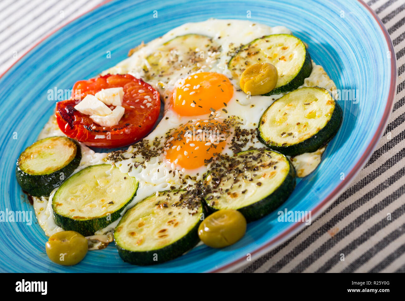 Délicieux oeufs au plat avec les courgettes et tomates servi avec fromage feta et olives Banque D'Images