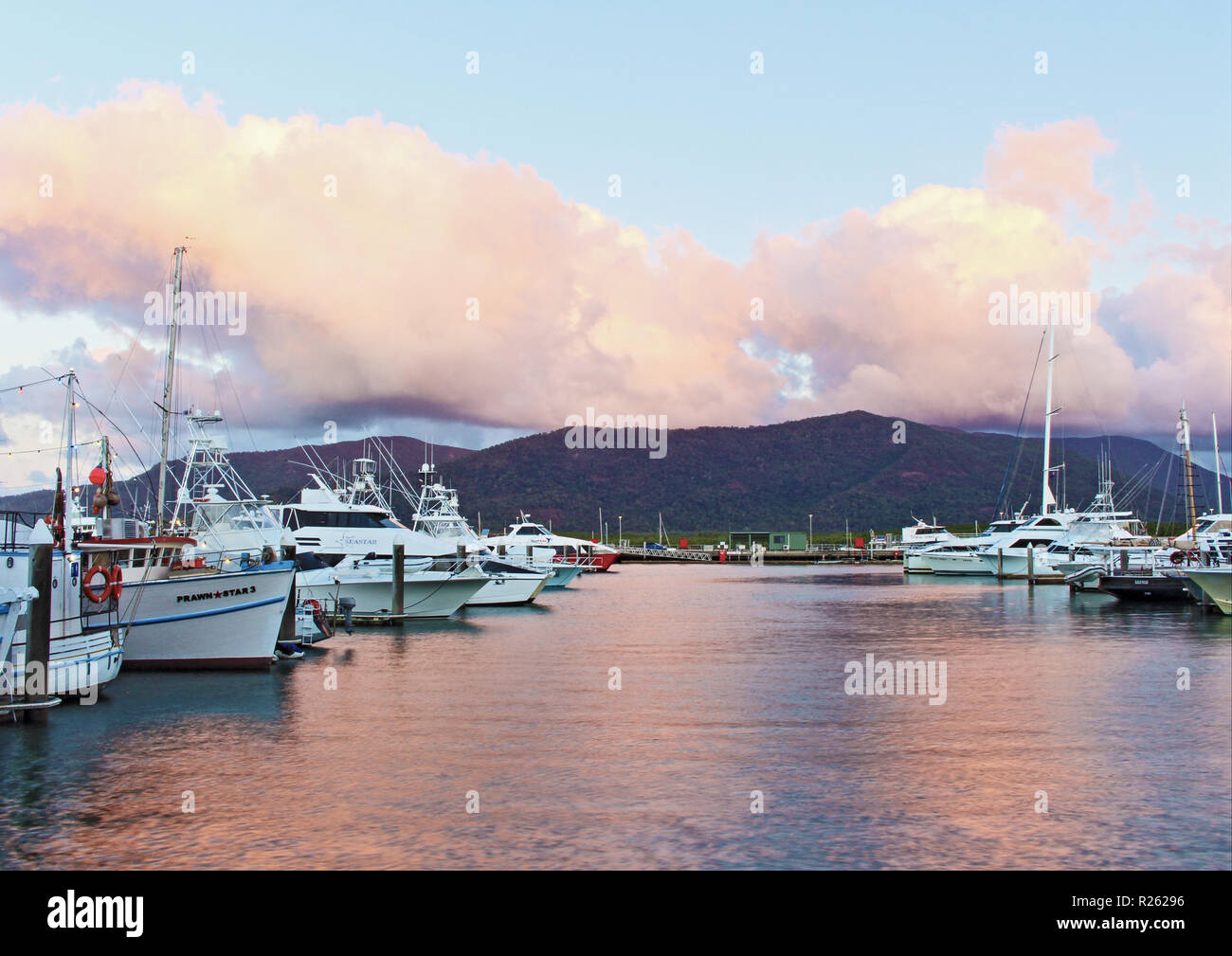 Coucher de Cairns sur une séquence de quelques minutes avec des nuages sur l'est le paramètre reflétant la trinité du soleil sur les eaux de la Cairns Marlin Marina Banque D'Images