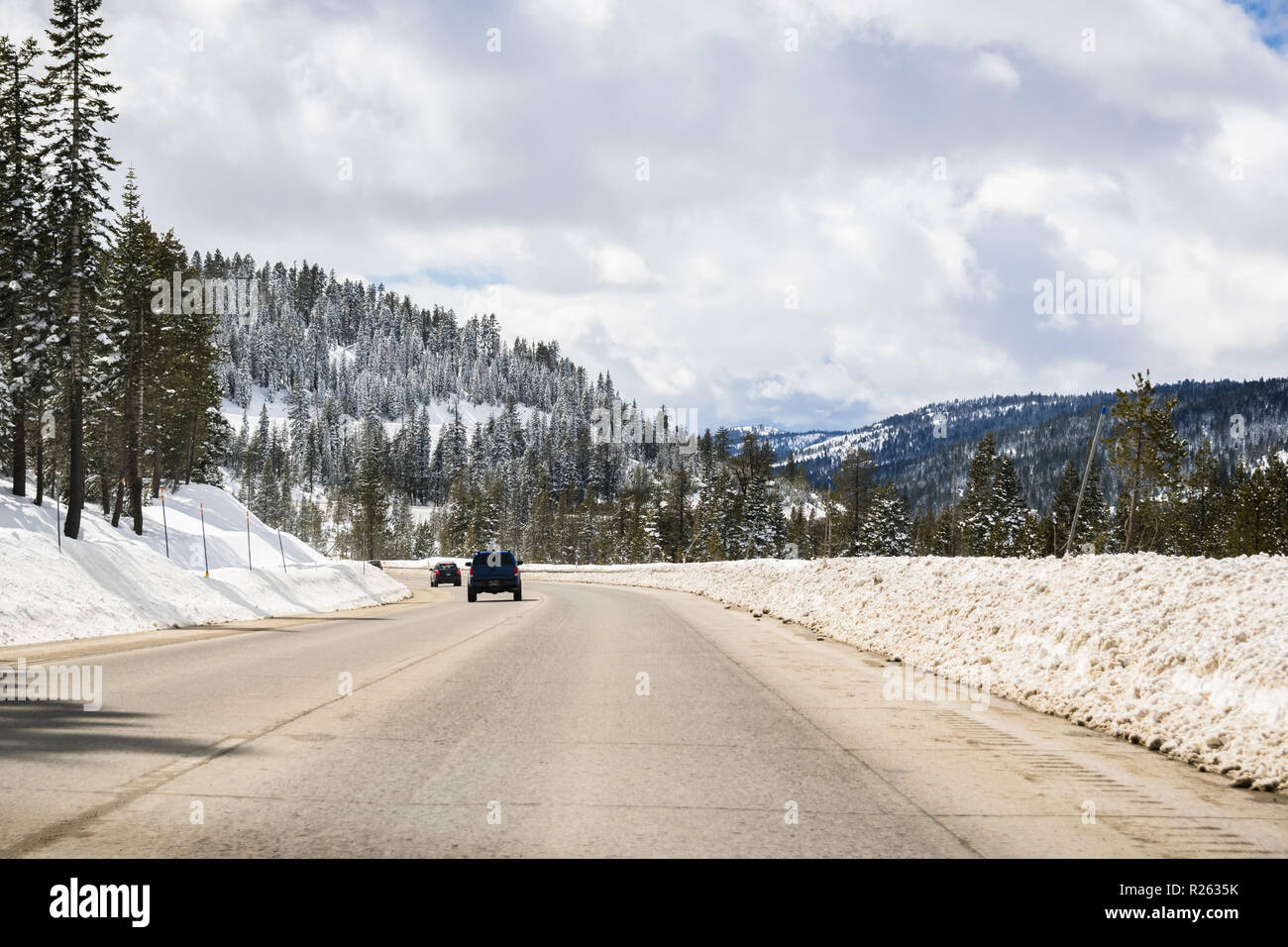 Les voitures qui circulent sur l'autoroute I80 à travers la Sierra montagnes à proximité du lac Tahoe sur une journée d'hiver ensoleillée ; la route a été effacé sur la neige, en Californie Banque D'Images