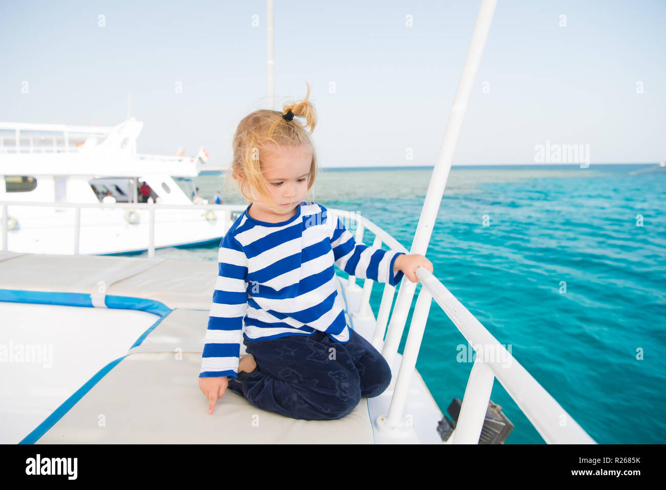 Petit marin bébé garçon enfant mignon ou capitaine de yacht, bateau ou  navire de couleur blanche avec des cheveux blonds en déshabillé chemise  marine outdoor le fond naturel avec bleu de la