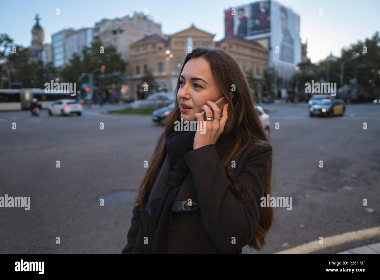 Young businesswoman marchant à travers la place et parler au téléphone Banque D'Images