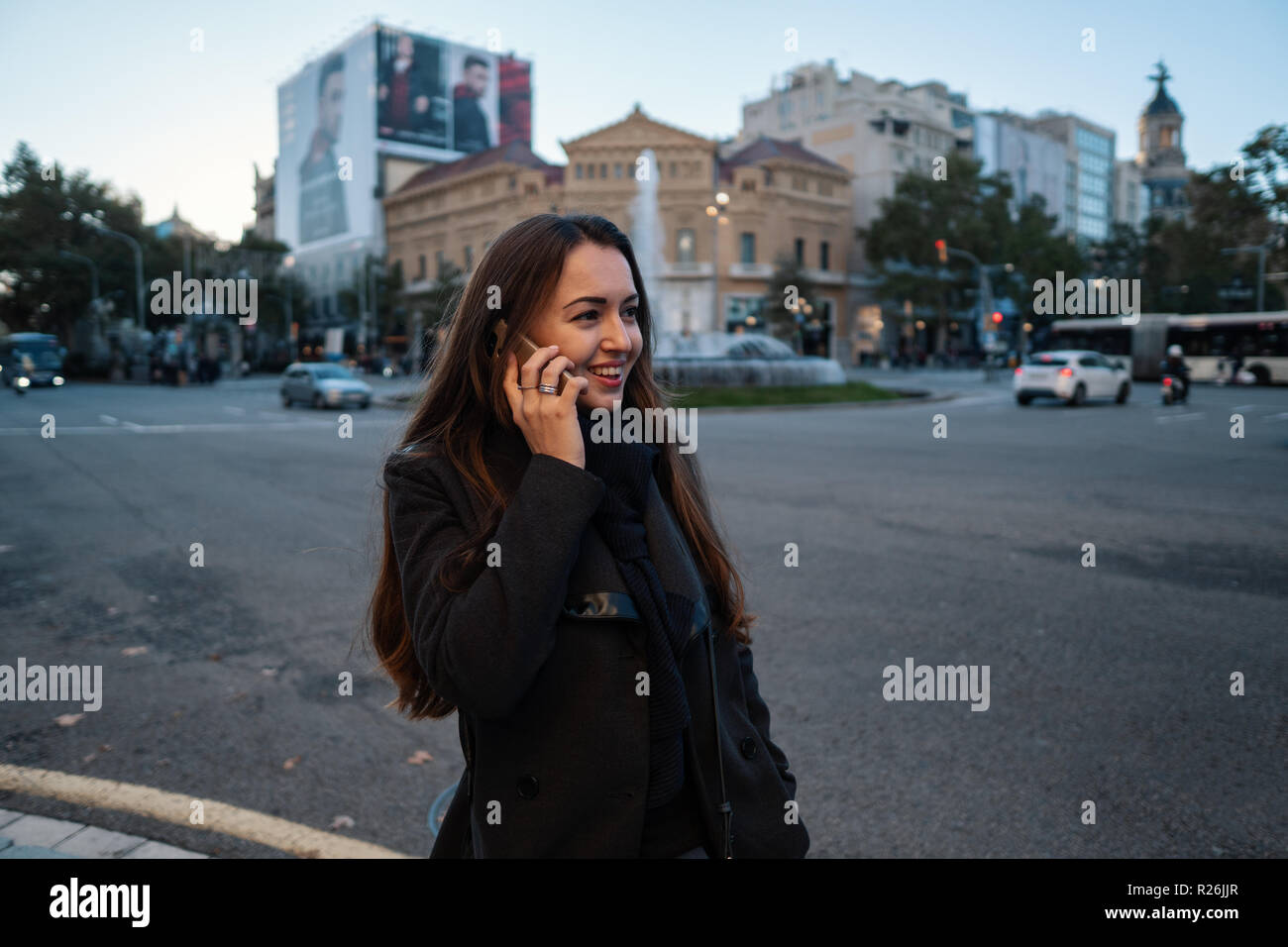 Young businesswoman marchant à travers la place et parler au téléphone Banque D'Images