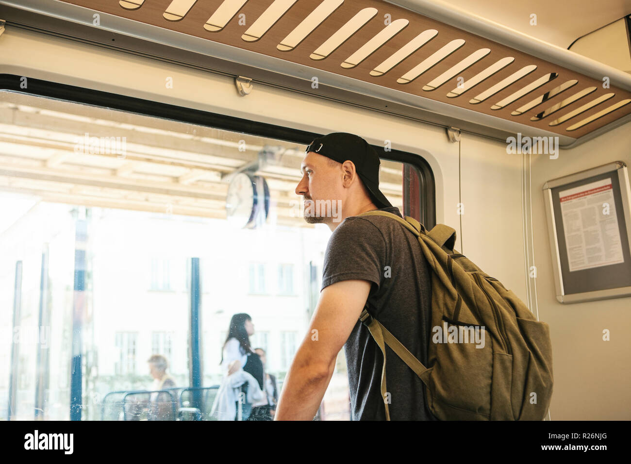 Un jeune mec avec un sac à dos à l'intérieur du train regarde par la  fenêtre à la gare Photo Stock - Alamy