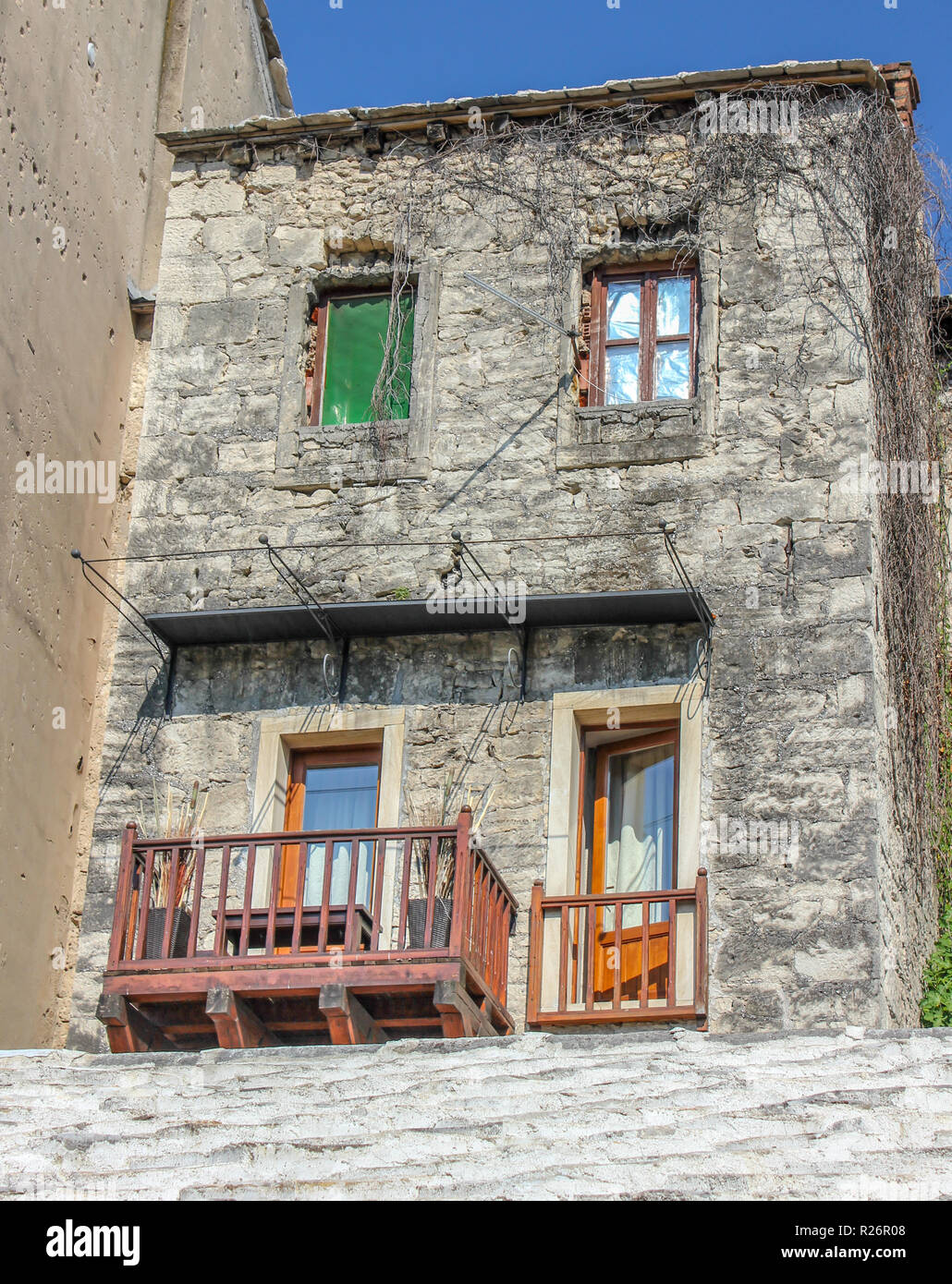 Août 2013, Mostar. Une vieille maison en pierre traditionnelle avec balcon terrasse dans la vieille ville. Trous de balle de la guerre sont visibles sur le mur de la nex Banque D'Images