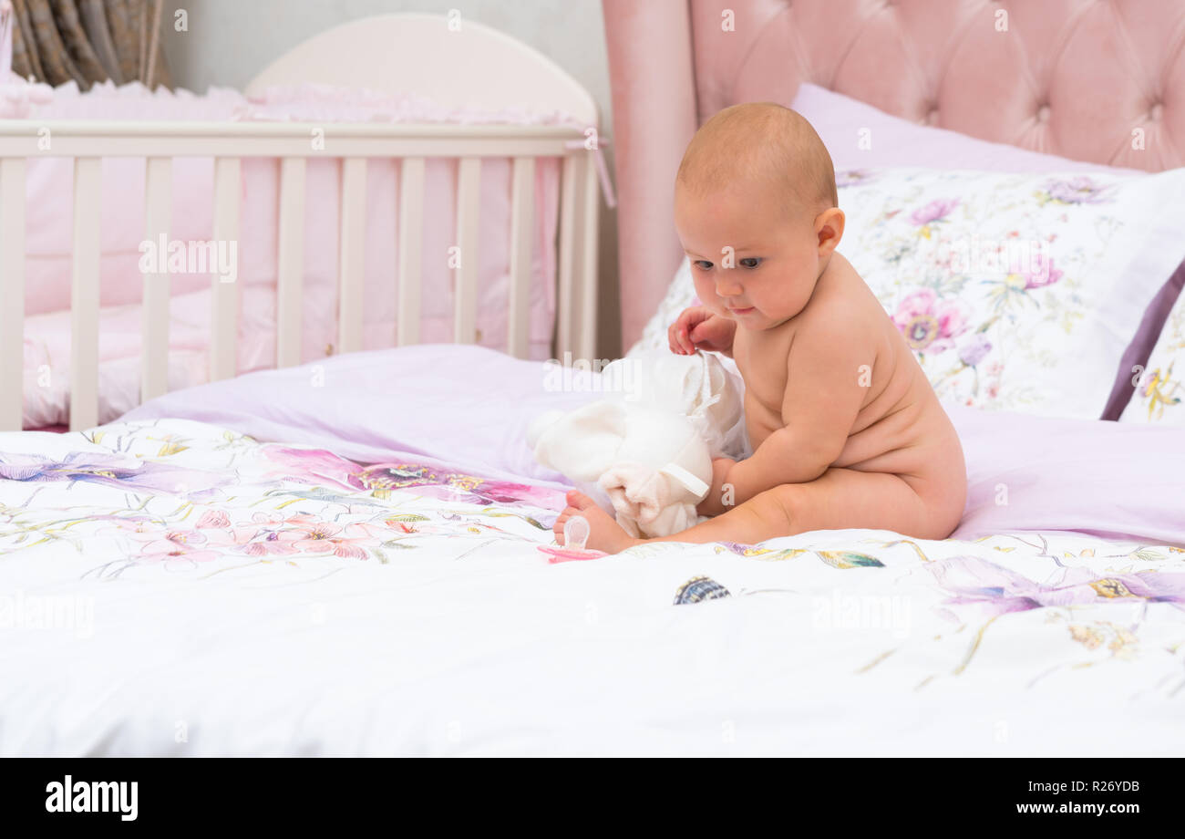Jeune Bebe Avec Visage Serieux Joue Avec Toy Assis Sur Le Lit Avec Pas De Vetements Pleine Longueur Tourne Dans La Chambre Des Parents Avec Copie Espace Photo Stock Alamy