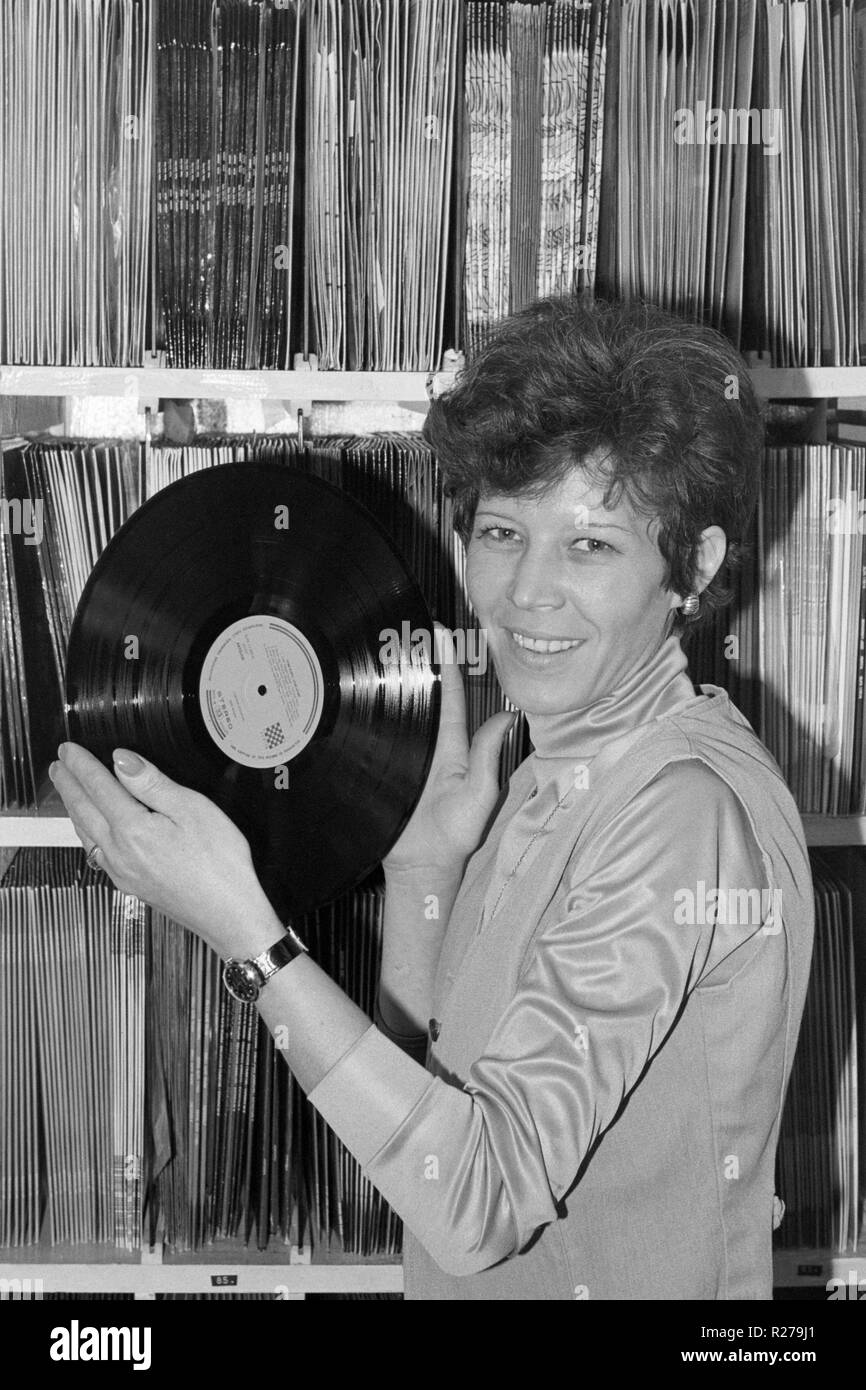 Smiling woman holding up un vinyl lp album dans un magasin de disques des années 70, la Hongrie Banque D'Images