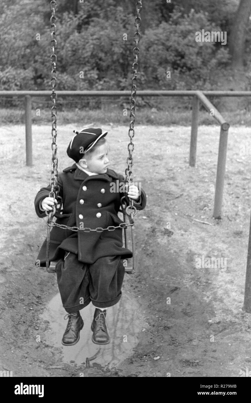 Jeune garçon assis sur une balançoire dans un parc 1950 Hongrie Banque D'Images