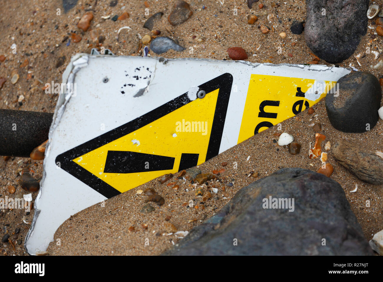 Panneau d'avertissement de danger à moitié enfoui sous le sable. Banque D'Images