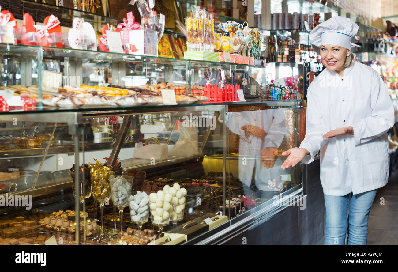 Personnes âgées cheerful vendeur avec dark et blanc Chocolats Confiseries à afficher Banque D'Images