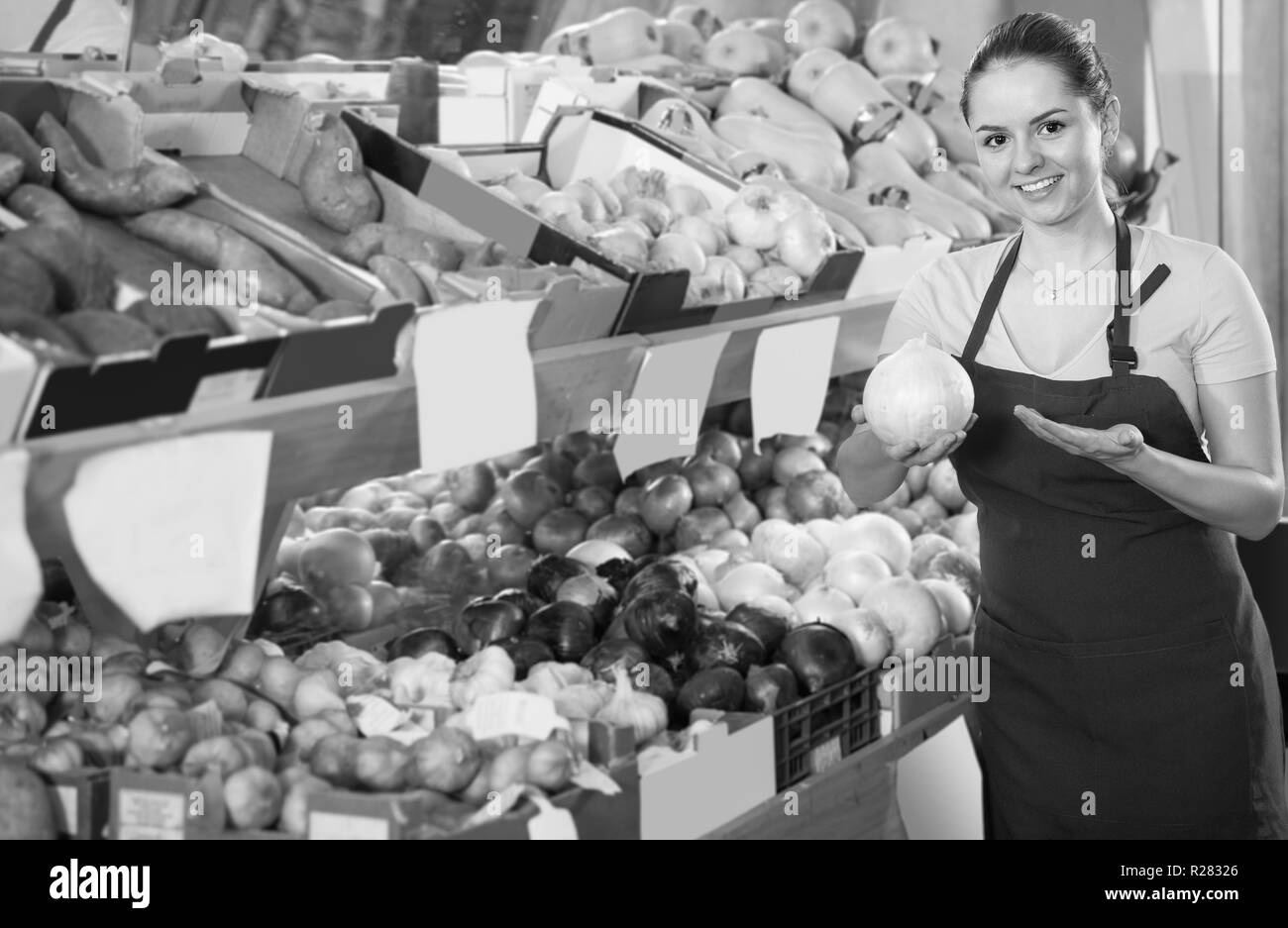 Portrait of young smiling saleswoman in store avec des oignons dans les mains Banque D'Images