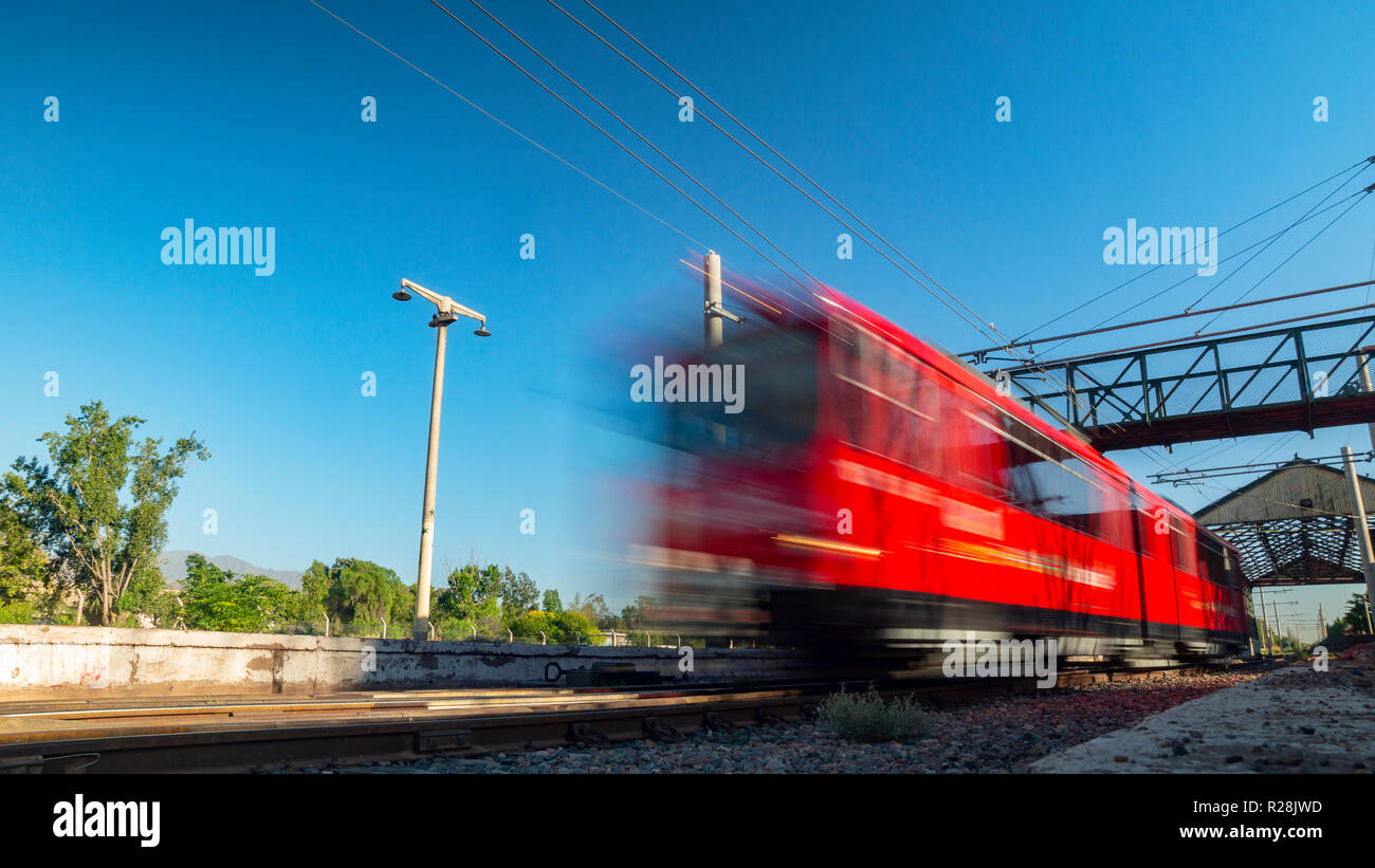 Train rouge se déplaçant à une vitesse élevée sur un jour ensoleillé sans nuages Banque D'Images