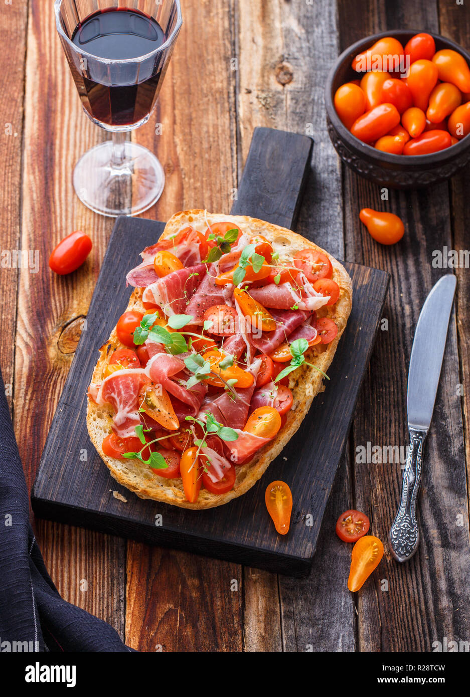 Bruschetta au jambon, tomate et basilic sur planche de bois de style rustique, copiez l'espace. Banque D'Images