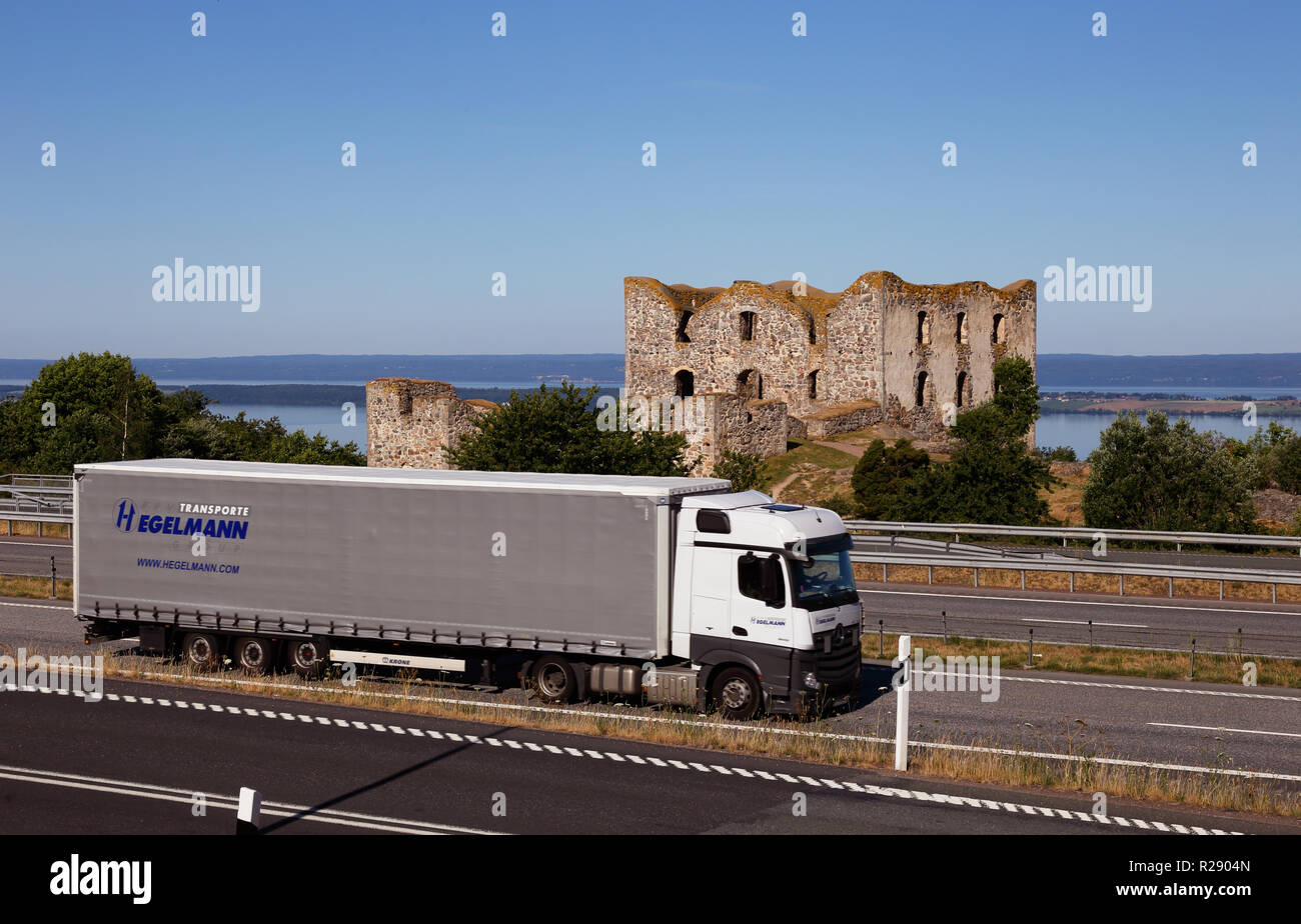 Granna, Suède - 26 juin 2018 : l'autoroute E4 numer avec chariot devant des ruines du château de l'Brhaehus avec vue sur le lac Vattern. Banque D'Images