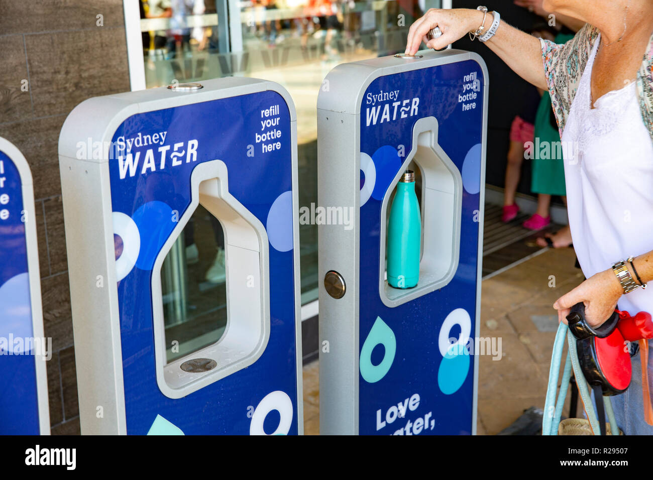 Sa femme le remplissage d'une bouteille de boisson de l'eau de Sydney street,Sydney, Australie Banque D'Images