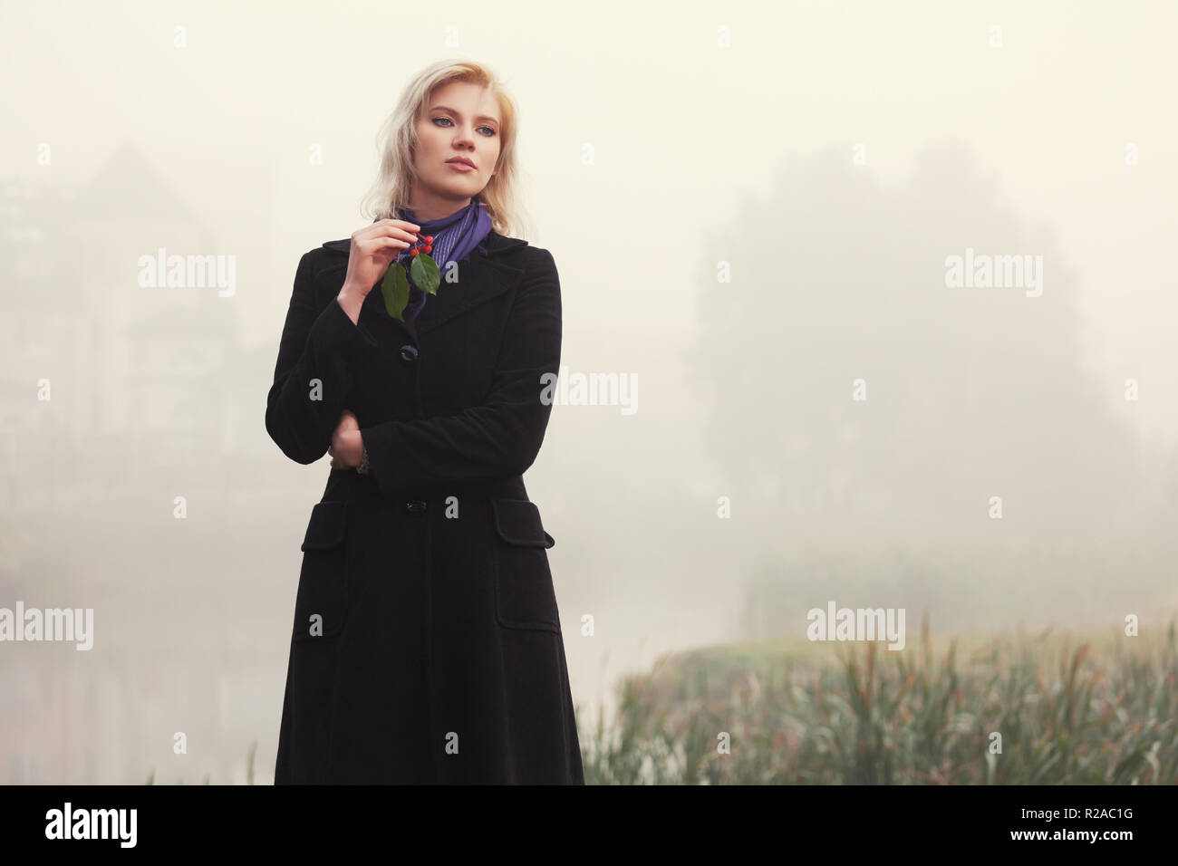 Sad young woman walking by the lake dans le brouillard. Modèle de mode élégant manteau noir classique en piscine Banque D'Images