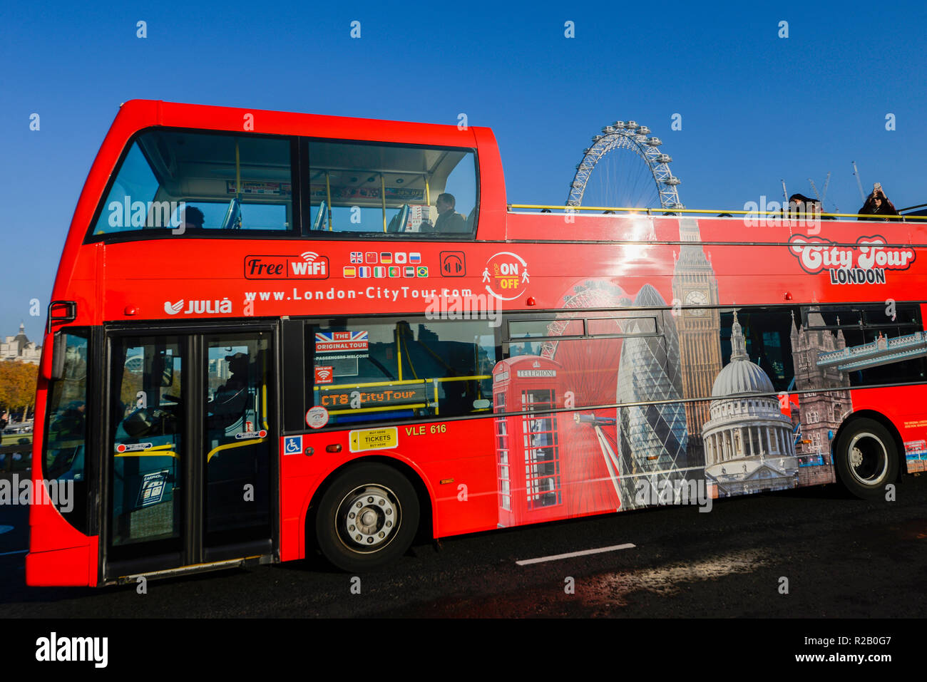 Visite de la ville de London red bus à toit ouvert avec vue sur les bâtiments emblématiques, avec le London Eye (grande roue du millénaire dépassant du haut. Tourisme Banque D'Images