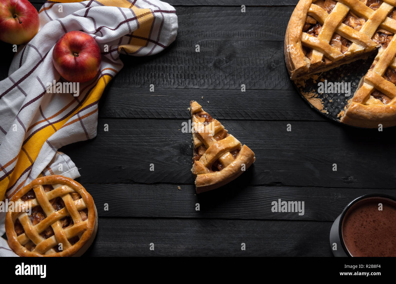 Table rustique de différentes tailles avec des tartes aux pommes et une coupe au milieu, une serviette, de pommes et de chocolat chaud. Vue ci-dessus. Des desserts traditionnels. Banque D'Images